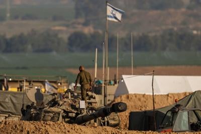 An Israeli solider walks on a mobile artillery unit near the Israel-Gaza border in southern Israel